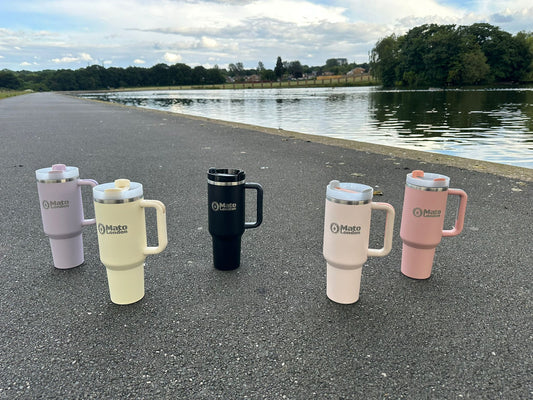 Mato London 40oz stainless steel tumblers in pastel colours by a lake – eco-friendly travel mugs ideal for spring hydration and outdoor adventures.