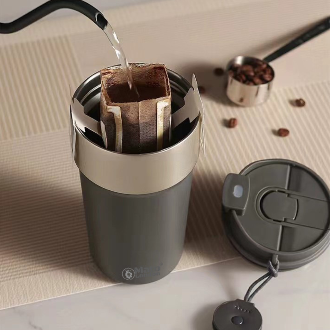 Mato London grey insulated stainless steel coffee cup with silver lid, reusable travel mug for hot drinks, shown with coffee being poured

